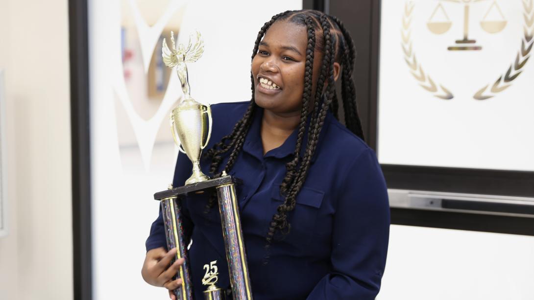 Casey Dozier smiles as she holds her InvestWrite trophy.