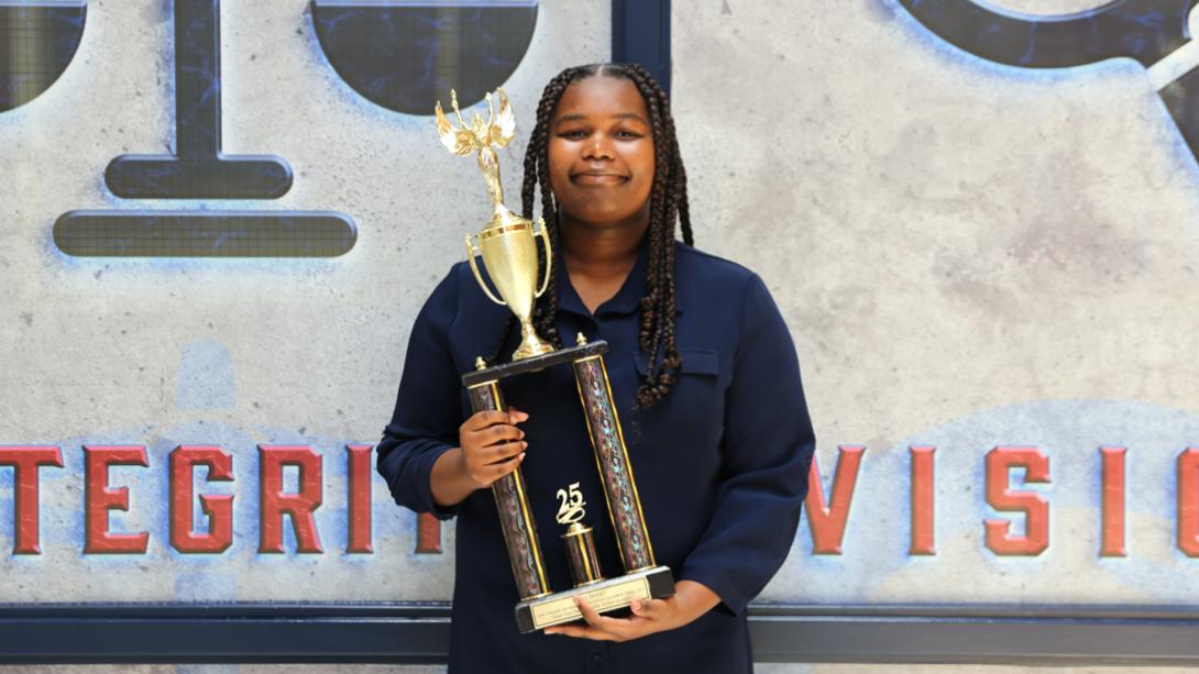 Casey Dozier smiles while holding her InvestWrite trophy.