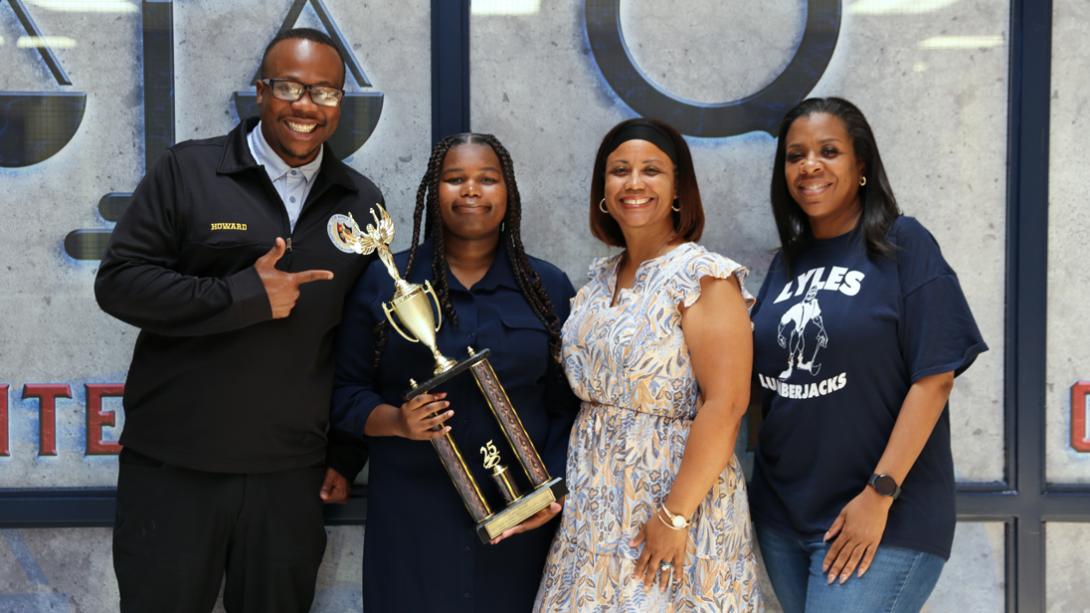 The Lyles MS principal and staff members smile alongside Casey for a photo with her trophy.