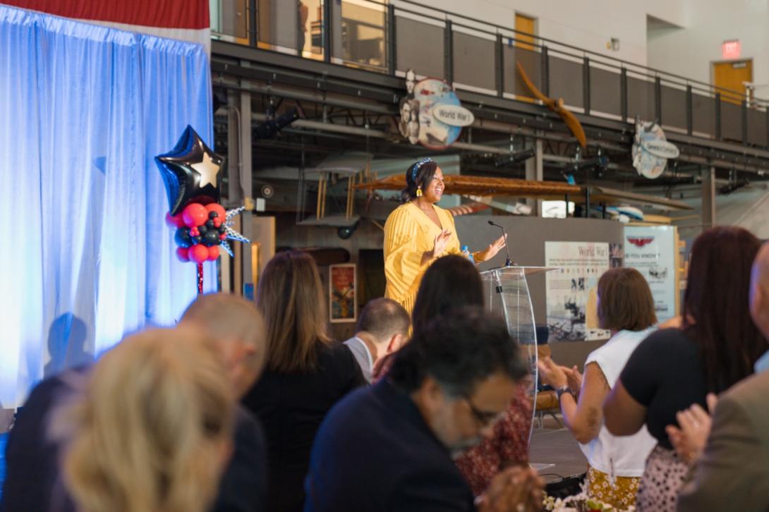 Ashley Ross stands at a podium giving an acceptance speech