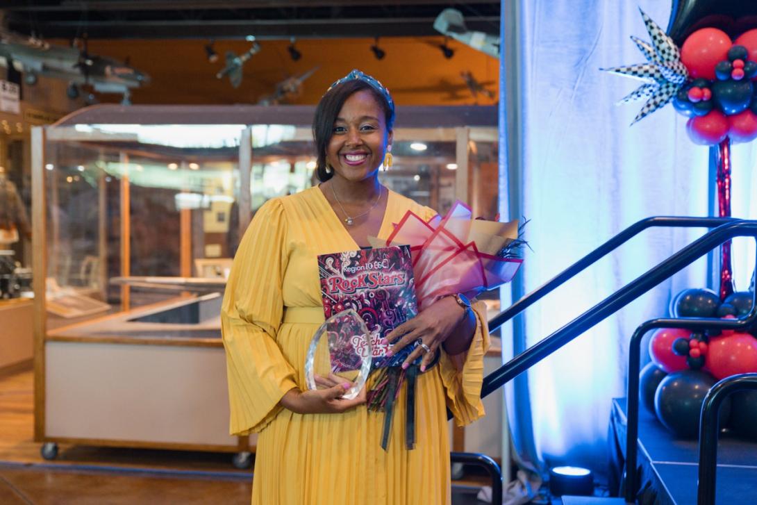 Ashley Ross stands with plaque and flowers