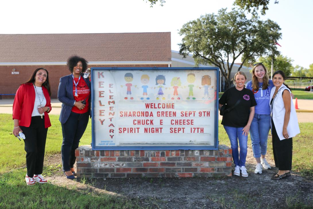 A group of five women stand in front of the Keeley Elementary marquee sign