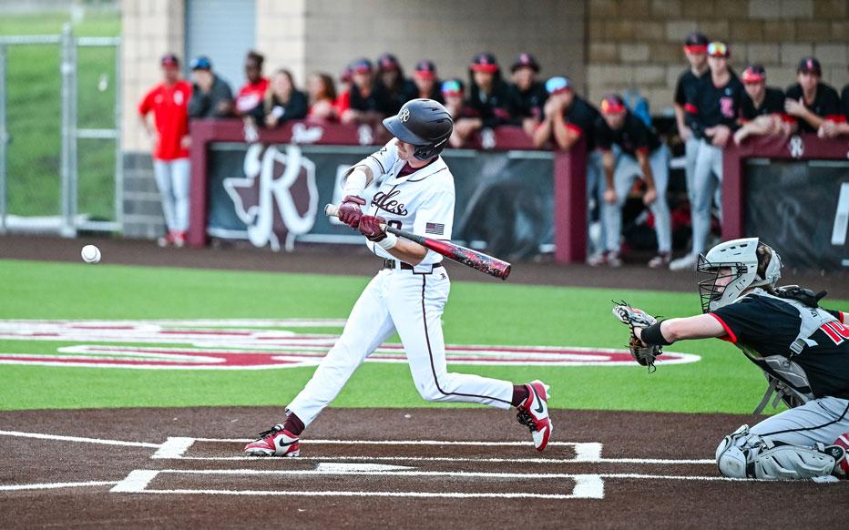 Eagles batter taking a swing with players in dugout watching in the background