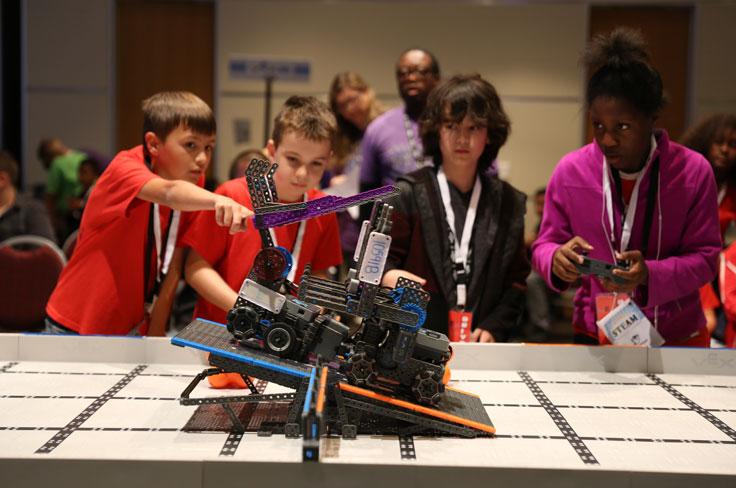4 students stand ready to test their robot