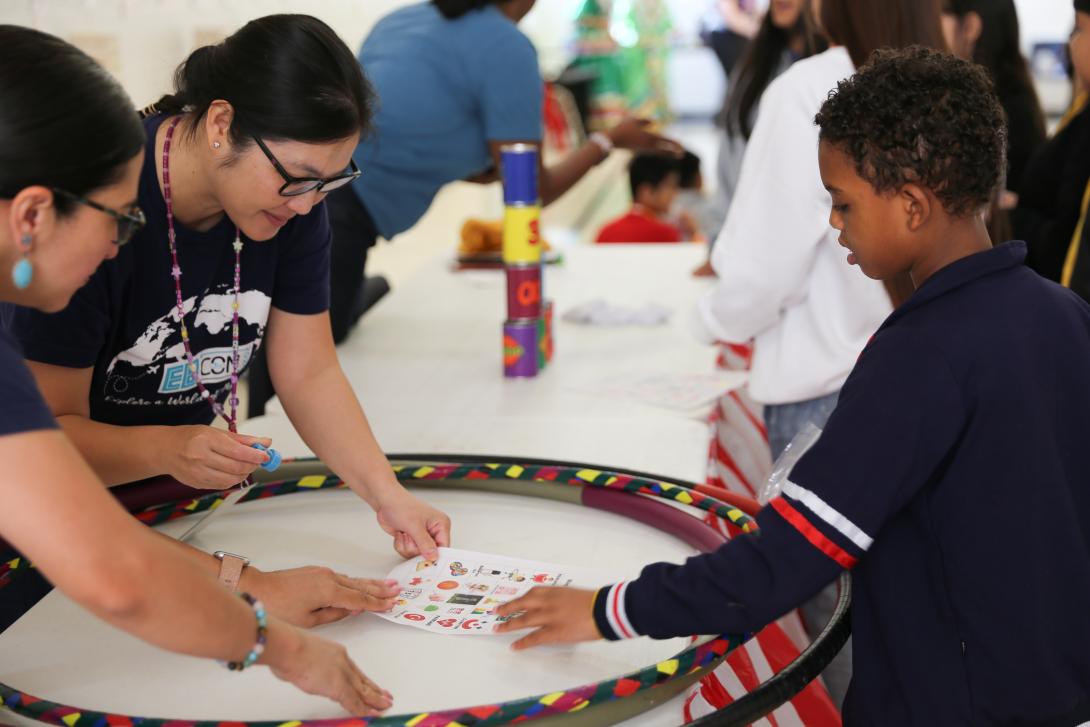 Two female teachers help a male student with a bingo game