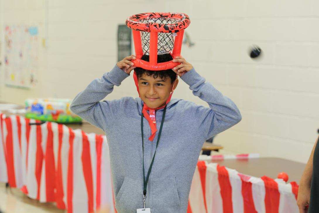 Student smiles with a basket toss game on his head