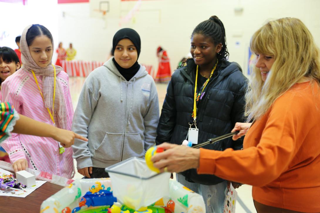 Three students and a teacher play a carnival game