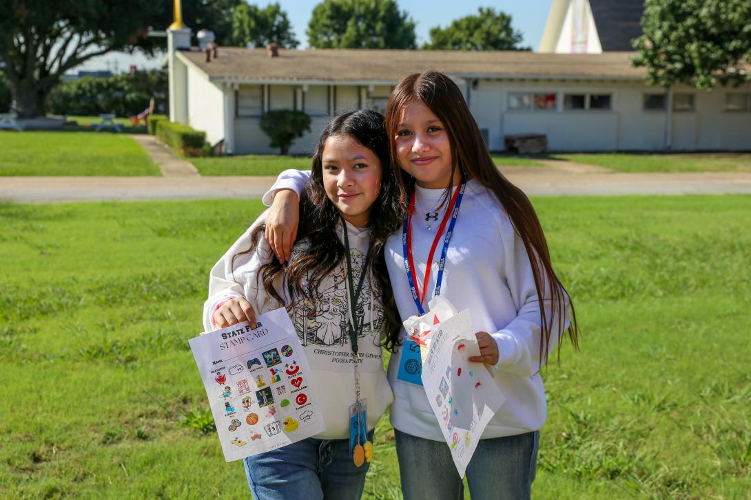Two female students embrace and smile