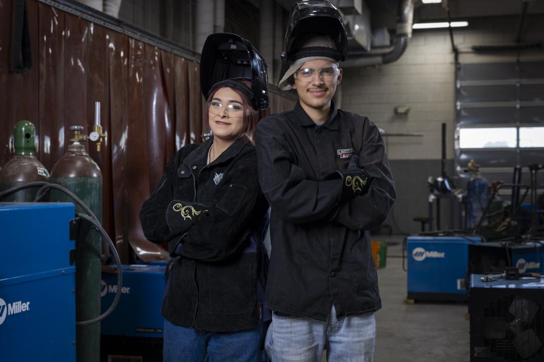 female and male welding students pose with their arms crossed