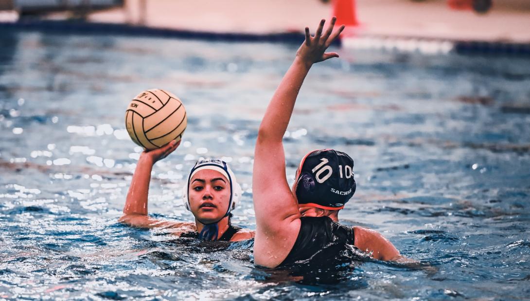 female water polo player attempts to score while a second player defends