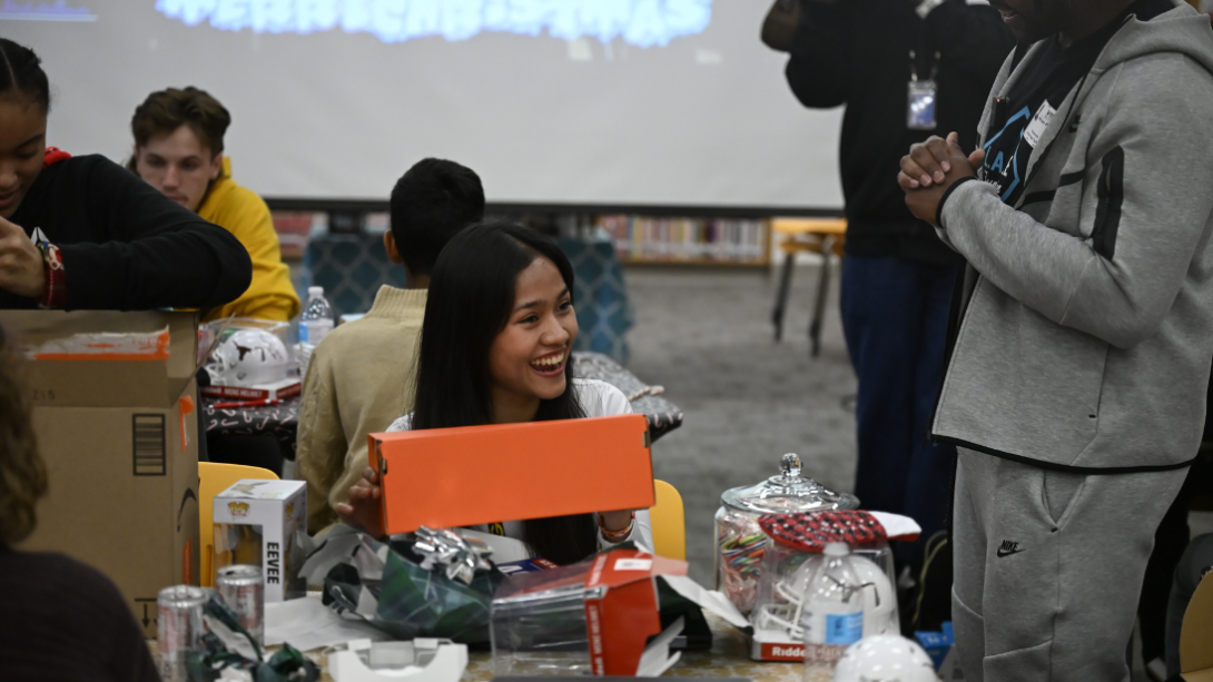 A student smiles as she opens a gift