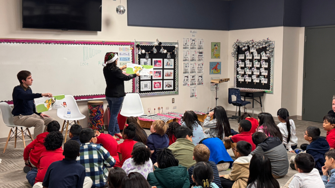 An adult woman reads to a group of students