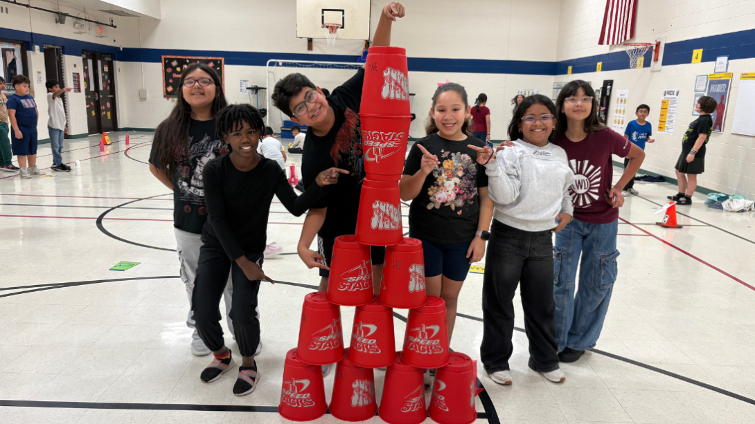 A diverse group of students pose with a tower of stacking cups