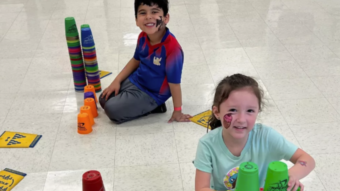 One female and one male student pose with towers of stacking cups