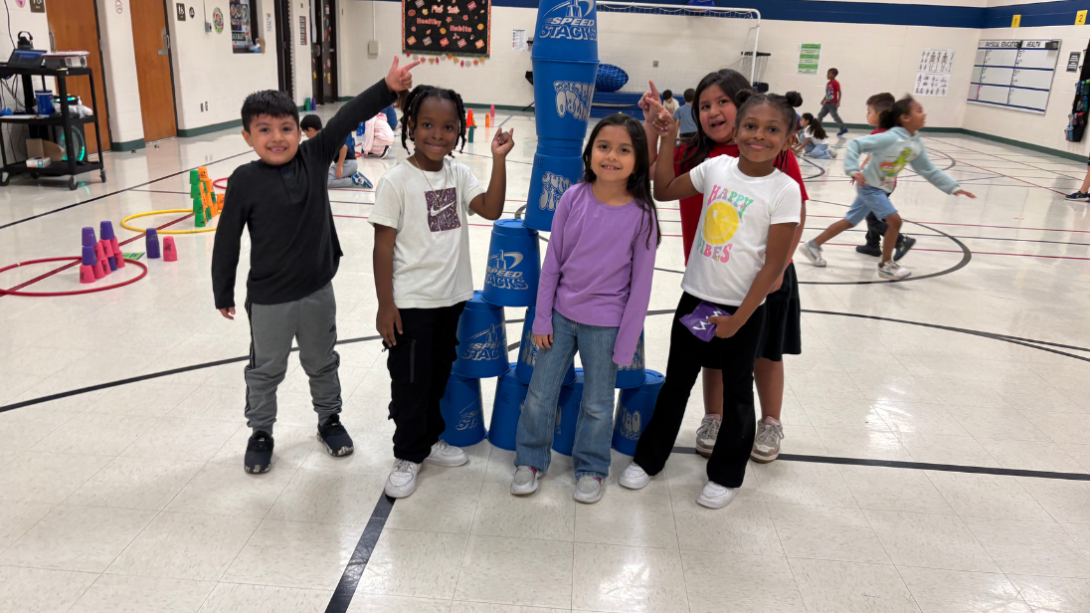 A diverse group of students pose with a tower of stacking cups