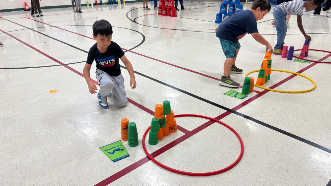 A diverse group of students pose with small towers of stacking cups
