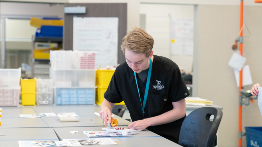 A male student sorts pills in pharmacy technician class