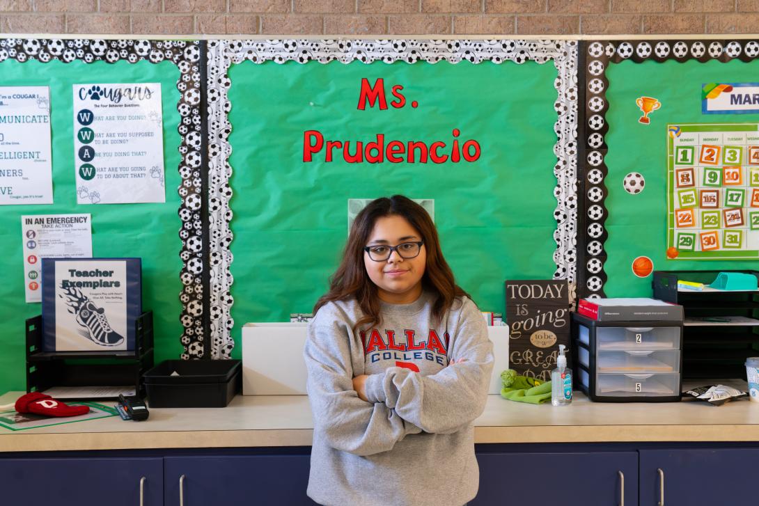a female teacher stands in front of a bulletin board