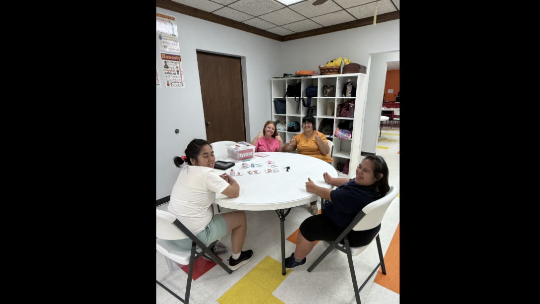 a female student sits with three special needs adults