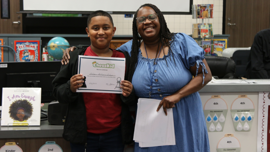 male student with certificate stands with female teacher