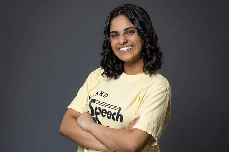 Jasmine John smiles and crosses her arms confidently