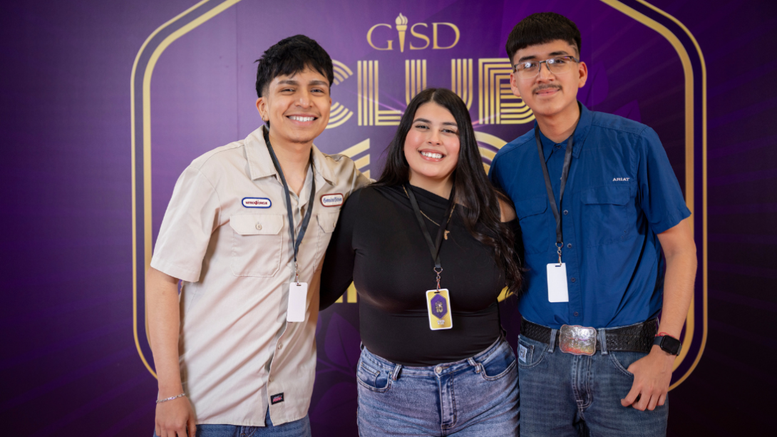 a group of three students stand in front of the backdrop