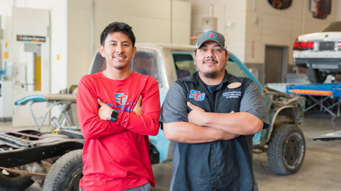 two male teachers stand in front of an vehicle chassis