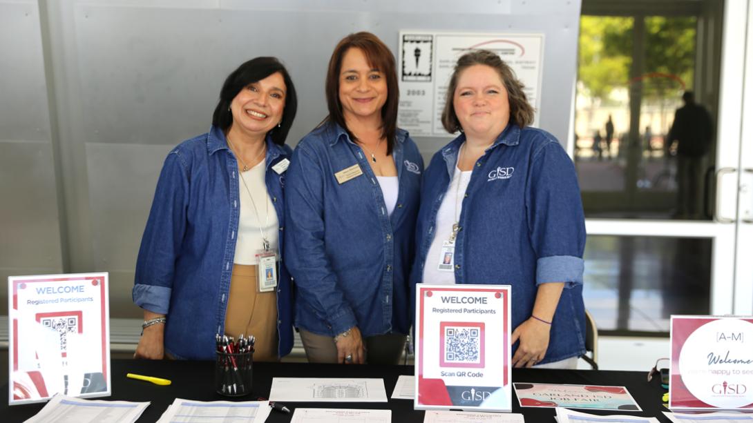 Three GISD HR reps smile at the registration table.