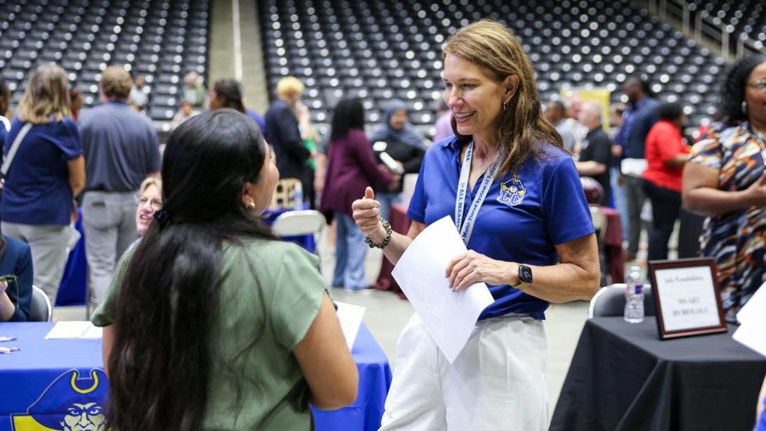 A Lakeview Centennial HS staff member smiles while chatting with a prospective employee in the arena.