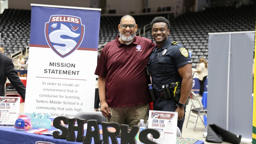 An admin at Sellers Middle School smiles and poses with a police officer.