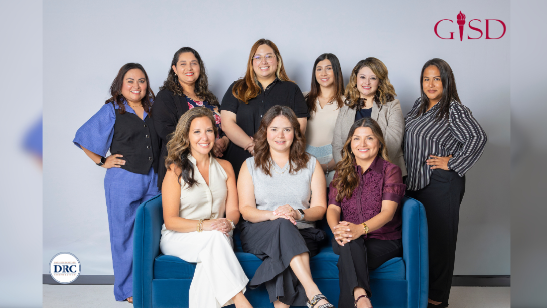 a group of adult women sit and stand while smiling straight on at the camera
