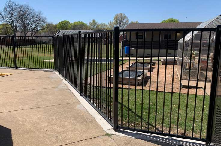 Perimeter fencing at Luna with greenhouse and garden beds in the background.