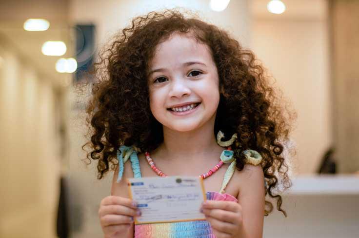 Smiling girl holding immunization record